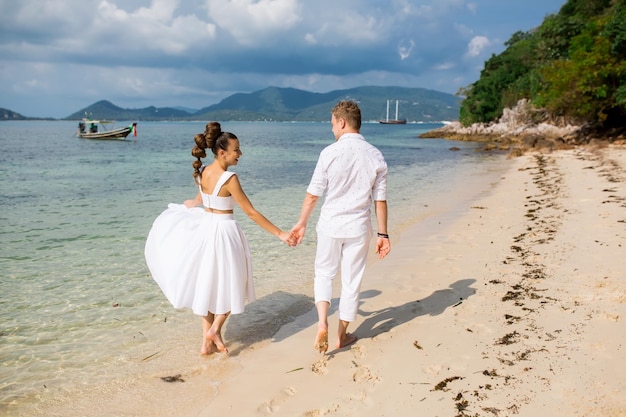 Zdjęcie męski pan młody i panna młoda chodzą boso po plaży