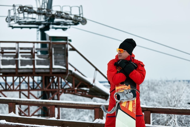 Męski Snowboardzista W Czerwonym Garniturze, Chodzenie Po Zaśnieżonym Wzgórzu Z Koncepcją Snowboardu, Narciarstwa I Snowboardu.