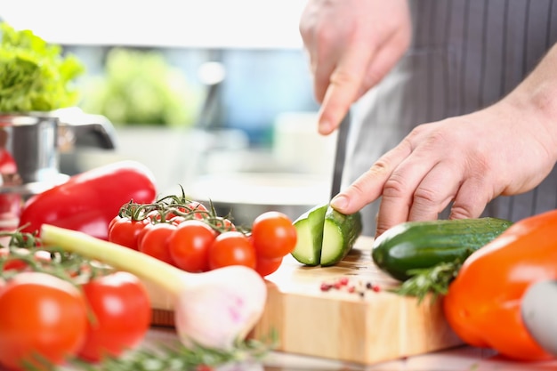 Męski szef kuchni przygotowuje zdrową sałatkę jarzynową ze świeżych składników organicznych