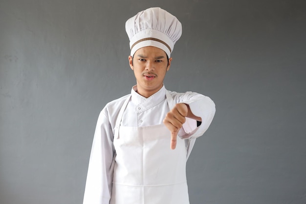 Męski szef kuchni w mundurze kuchennym robi znak niechęci po spojrzeniu na kulinarny posiłek obiadowy. Wesoły