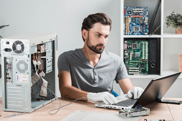 Męski technik używa laptop w warsztacie