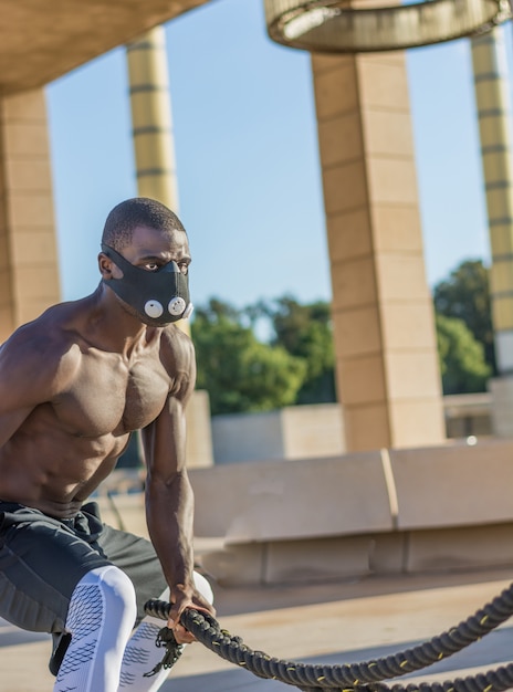 Męski trening mięśni z linami bojowymi i maską treningową