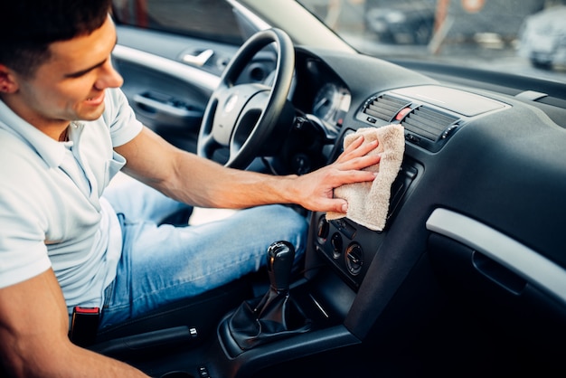 Męskie dłonie czyści auto, polerowanie deski rozdzielczej samochodu