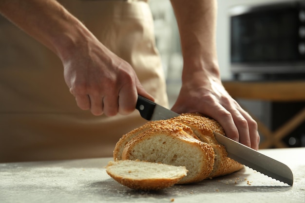 Męskie dłonie do cięcia pszennego chleba zbliżenie