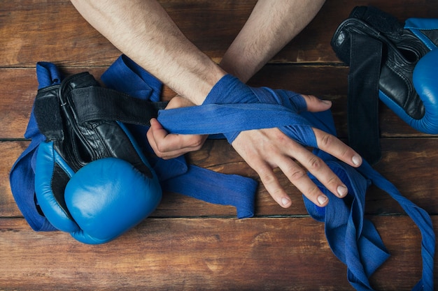 Zdjęcie męskie dłonie podczas taśmowania przed boksem dopasowują się do drewnianej powierzchni. pojęcie treningu do treningu boksu lub walki. leżał płasko, widok z góry