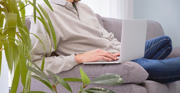 Męskie Dłonie, Pracując Na Laptopie, Siedząc Na Kanapie W Pozycji Jogi, Pracując W Domu.