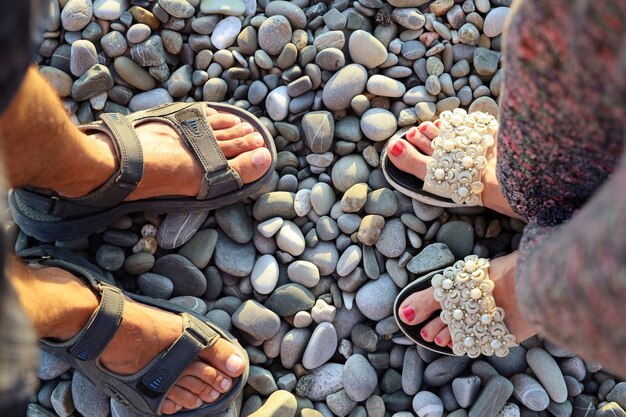 Męskie i żeńskie stopy kochanków w sandałach naprzeciw siebie na kamienistej powierzchni