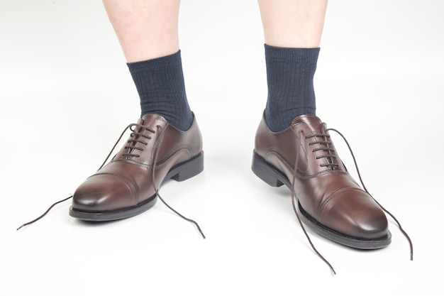 Męskie nogi w skarpetkach i brązowe klasyczne buty na białym tle