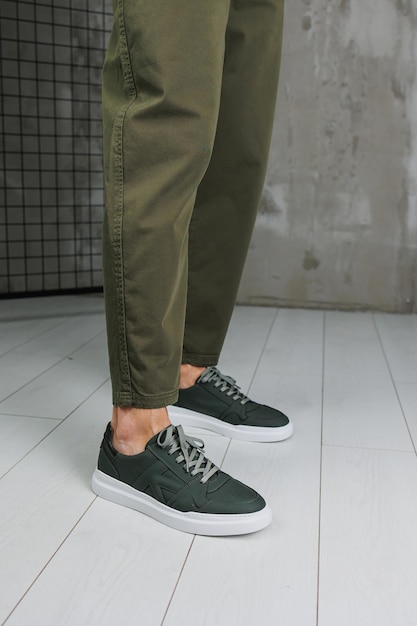 Męskie nogi w spodniach i zielonych trampkach Modne męskie buty