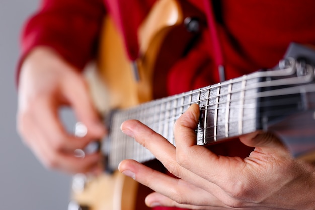 Męskie ramiona grające na gitarze elektrycznej o klasycznym kształcie