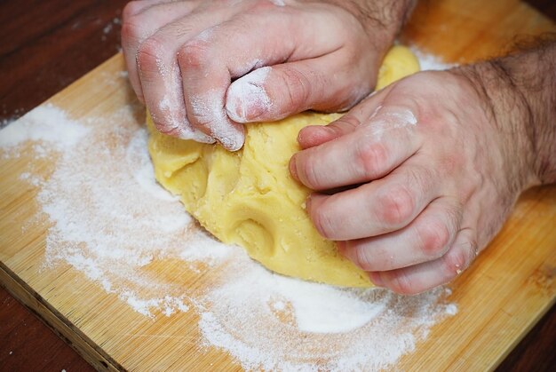 Męskie ręce wyrabiania ciasta na pizzę. Proces gotowania w piekarni