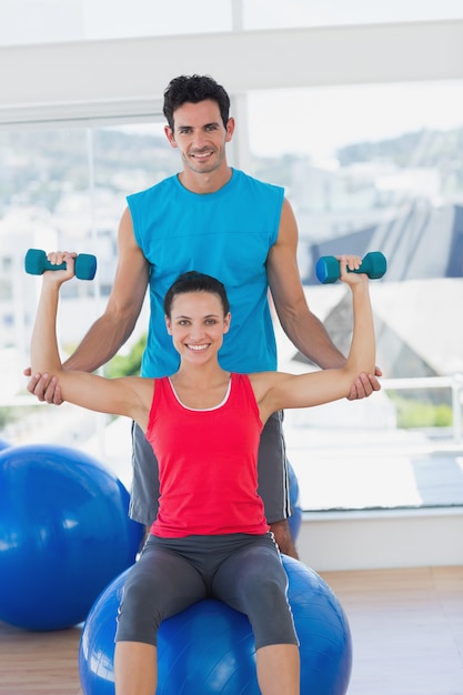 Męskiego trenera pomaga kobieta z jej ćwiczeniami przy gym