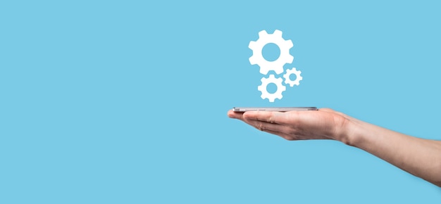 Zdjęcie męskiej ręki trzymającej ikonę koła zębate, ikona mechanizmu na wirtualnych ekranach na niebieskim tle. system automatyzacji procesu technologicznego koncepcja biznesowa. transparent.