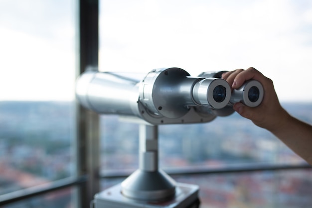 Męskiej ręki trzymającej lornetkę na tle panoramy z obserwatorium. Strzał zbliżeniowy