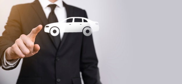 Męskiej ręki trzymającej samochód auto ikona na szarym tle. Szeroki baner