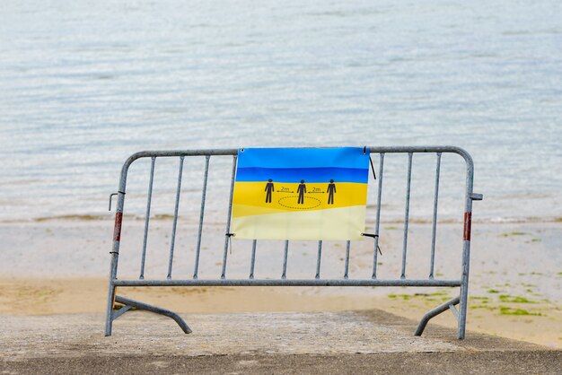 Metalowa bariera z plakatem utrzymuje odległość 2 metrów zainstalowana na plaży