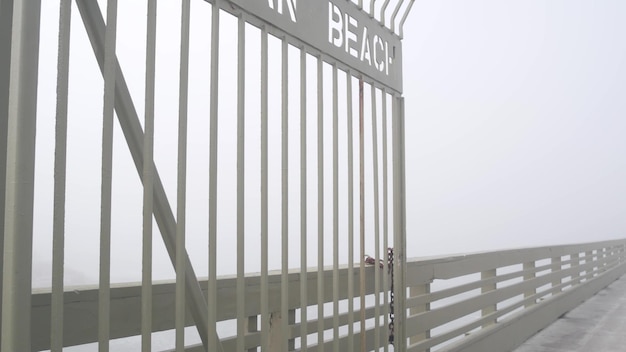 Metalowa brama molo na plaży oceanicznej we mgle zamglonej promenady wejście na wybrzeże Kalifornii
