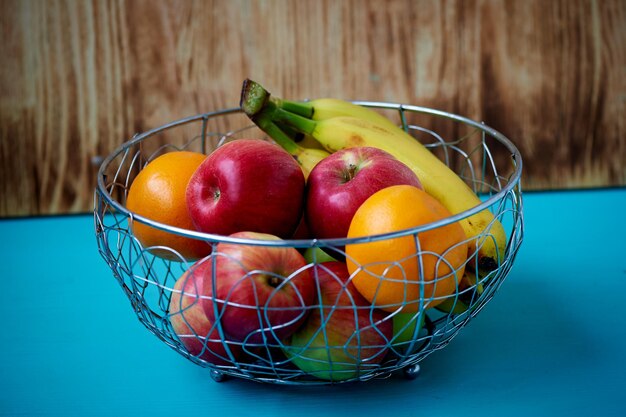 Metalowa miska na owoce na drewnianej powierzchni Zamknij Banany Pomarańcze i jabłka