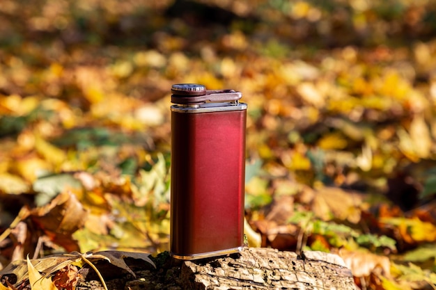 Metalowa piersiówka na alkohol w jesiennym lesie Jesienne spacery Męskie akcesoria podróżne