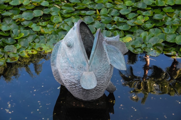 Metalowa statua rybki na ciemnym stawie