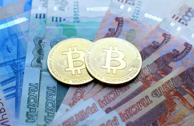 Metalowe błyszczące monety kryptowaluty bitcoin na banknotach rubli. Koncepcja pieniądza elektronicznego.