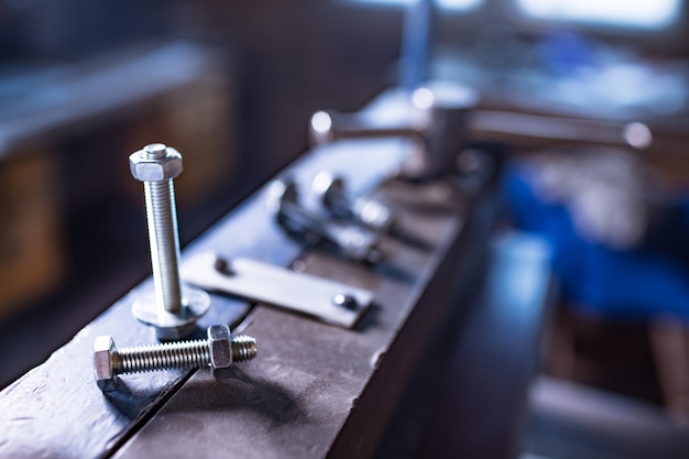 Metalowe chromowane śruby i nakrętki na ręcznej elastycznej masywnej maszynie. Stara klasyczna maszyna w stylu vintage retro część mechaniczna prasa budowlana do obróbki blachy stalowej