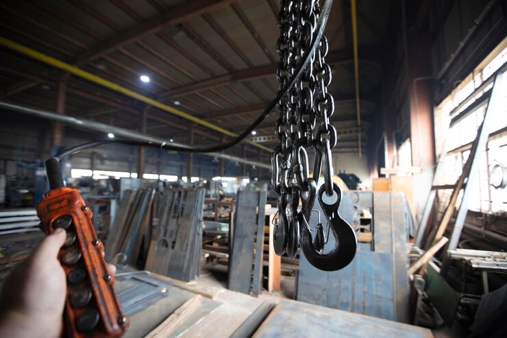 Metalowe łańcuchy przemysłowe z haczykami w warsztacie zakładu metalurgicznego