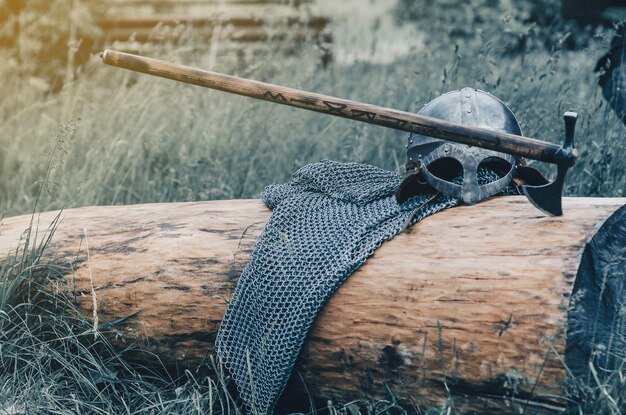 Zdjęcie metalowy hełm z łańcuchem i siekiera leżą na drewnianej broń wikingów koncepcja filmu historycznego