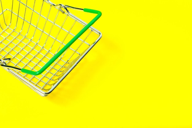 Zdjęcie metalowy kosz na żółtym tle na zakupy w supermarkecie.