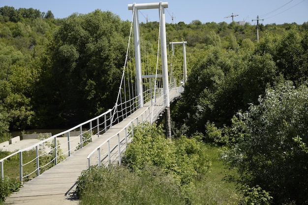 Metalowy most wiszący nad rzeką przez gęstą roślinność Uljanowsk Rosja