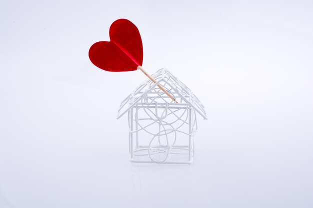 Zdjęcie metalowy przewodowy model domu i czerwony kształt serca