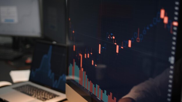 Zdjęcie mężczyzna analizujący zmiany na giełdzie na ekranie komputera domowego biura z wykresami