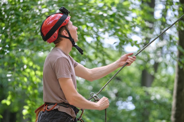 Mężczyzna asekuruje swojego partnera wspinacza za pomocą przyrządu asekuracyjnego i liny. Handman alpinisty trzymający sprzęt do zabezpieczenia alpinizmu.