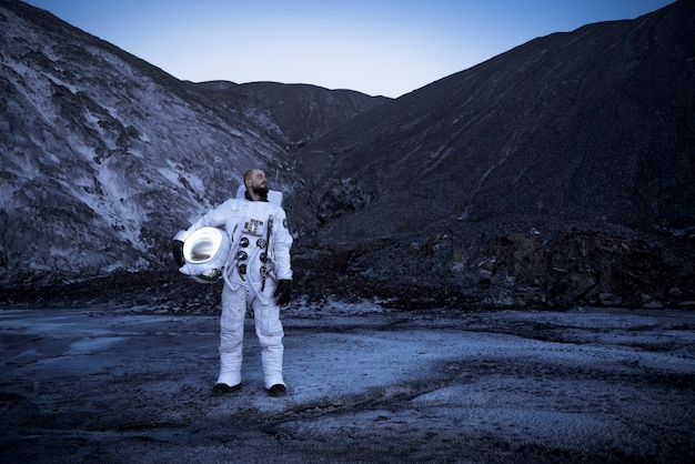 Zdjęcie mężczyzna astronauta trzymający hełm podczas misji kosmicznej na nieznanej planecie