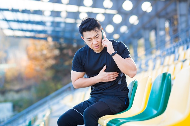 Mężczyzna azjatycki biegacz ma silny ból w klatce piersiowej, ból serca po bieganiu i treningu, wezwanie karetki pogotowia szybko wezwie lekarza