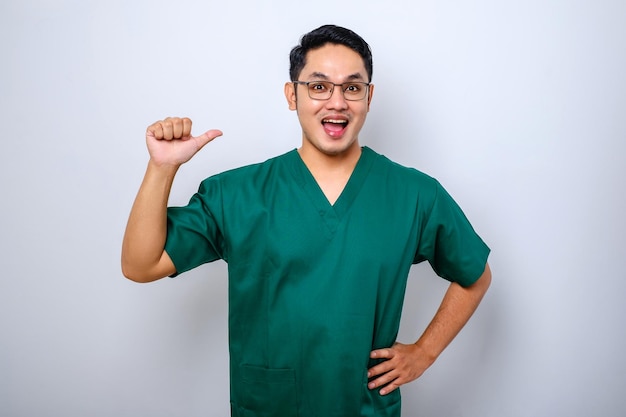Mężczyzna azjatycki lekarz pielęgniarka w zaroślach wskazuje na siebie i uśmiecha się
