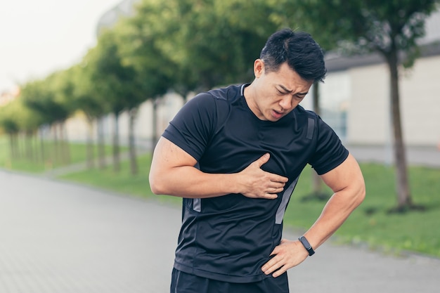 Mężczyzna Azjatycki Sportowiec, Ma Ból W Klatce Piersiowej W Parku I Biega, Bóle Serca Po ćwiczeniach Cardio