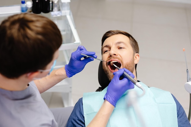 Zdjęcie mężczyzna badający zęby u dentystów przegląd profilaktyki próchnicy zębów