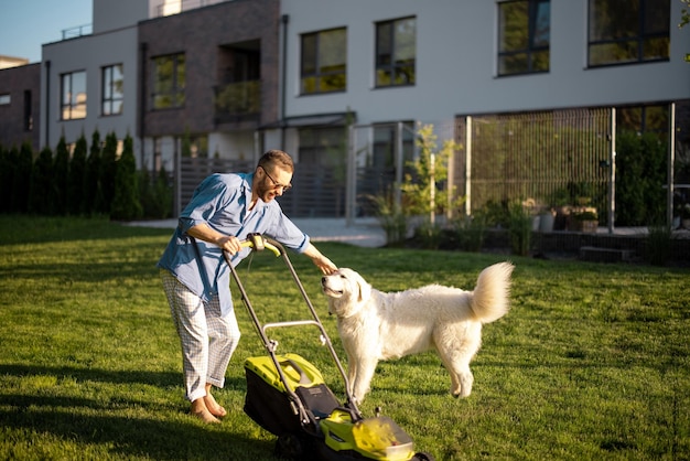 Mężczyzna bawi się z psem podczas przesuwania trawnika na podwórku