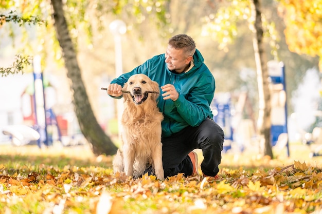 Mężczyzna bawiący się ze swoim psem golden retriever w parku