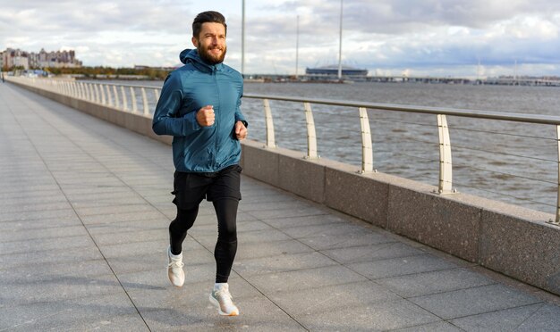 Mężczyzna biega sam trenując na zimnie Sportowiec biegający w ciepłych ubraniach sportowych na jesień Trener fitness