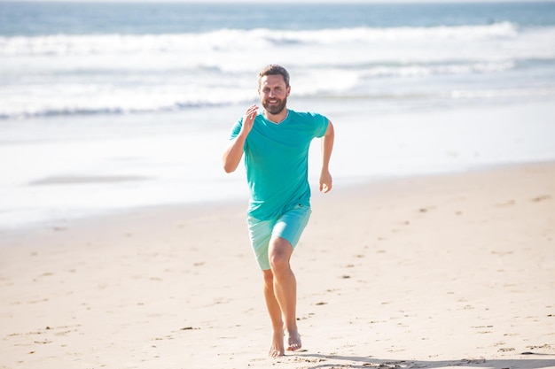 Mężczyzna biegacza sportowiec biega po piaszczystej plaży Mężczyzna biega