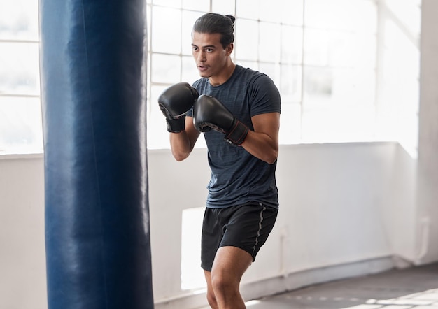 Mężczyzna boks i trening z workiem treningowym na siłowni dla zdrowia i dobrego samopoczucia ciała z rękawicami bokserskimi Bokserskie sztuki walki lub ćwiczenia sportowe cardio lub skupienie się z precyzją w studio