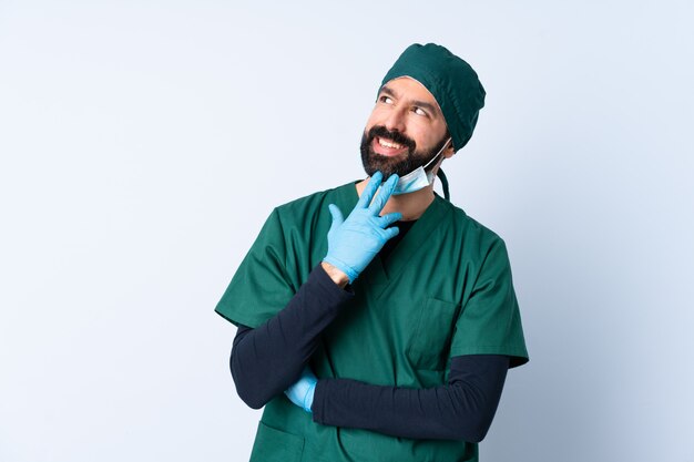 Mężczyzna chirurg w zielonym mundurze na ścianie patrząc w górę, uśmiechając się