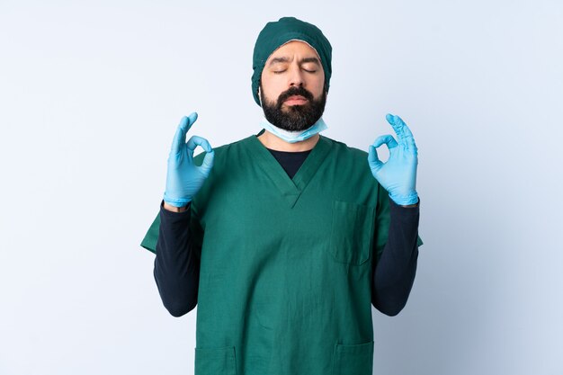 Mężczyzna chirurg w zielonym mundurze nad ścianą w pozie zen