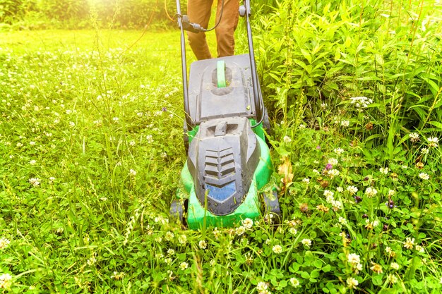 Mężczyzna cięcia zieloną trawę z kosiarki na podwórku. Ogrodnictwo tabeli stylu życia kraju