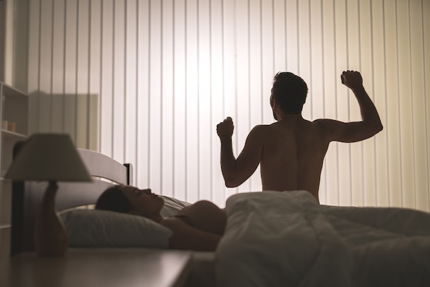 Mężczyzna ćwiczący w pobliżu kobiety na łóżku