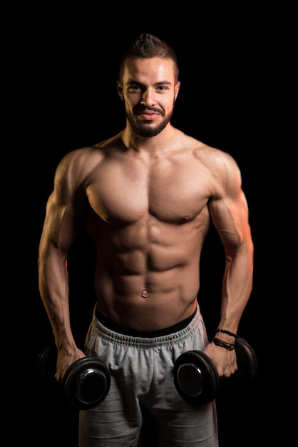 Mężczyzna Ćwiczenia Biceps Z Hantlami Na Czarnym Tle
