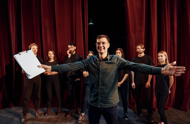 Zdjęcie mężczyzna ćwiczy swoją rolę grupa aktorów w ciemnych ubraniach na próbie w teatrze