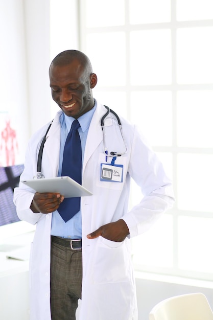 Mężczyzna czarny lekarz pracownik z komputerem typu tablet stojący w szpitalu
